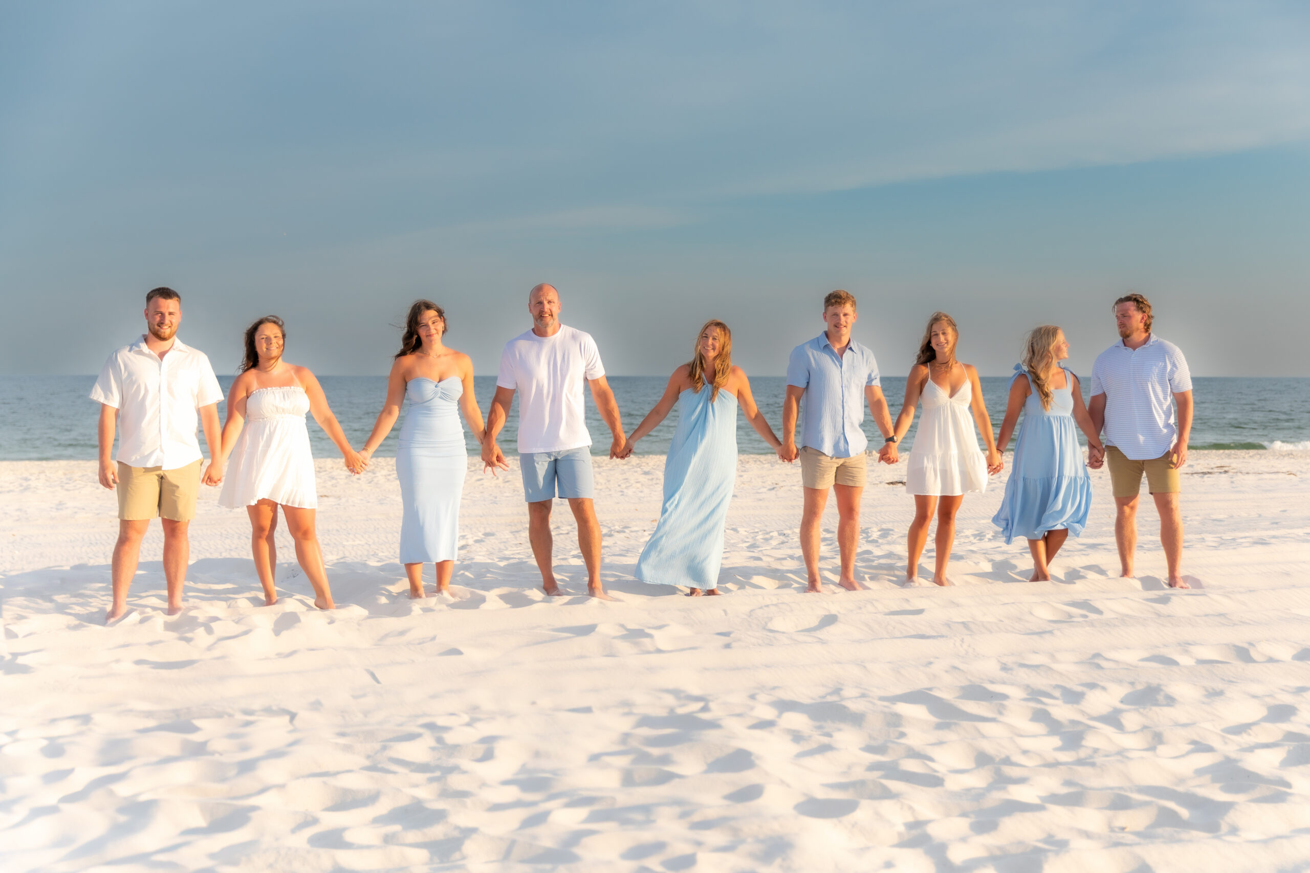 Group holding hands on white sandy beach